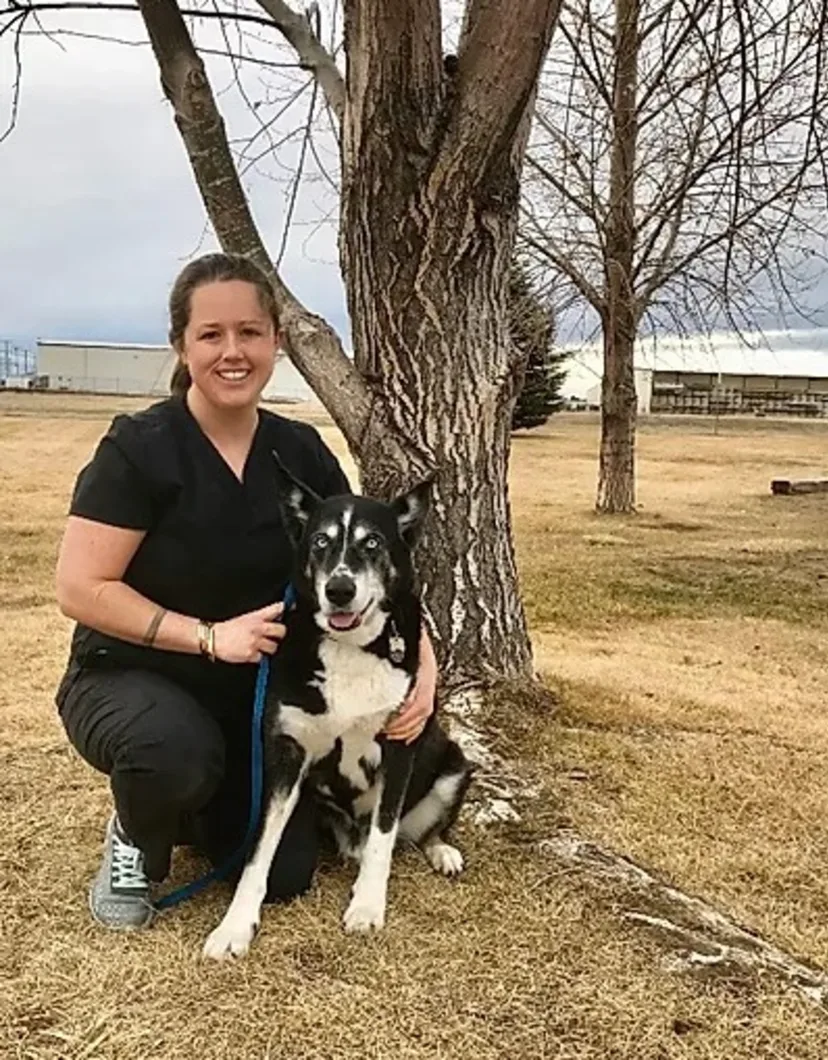 Katie T. kneeling in front of a tree with her dog